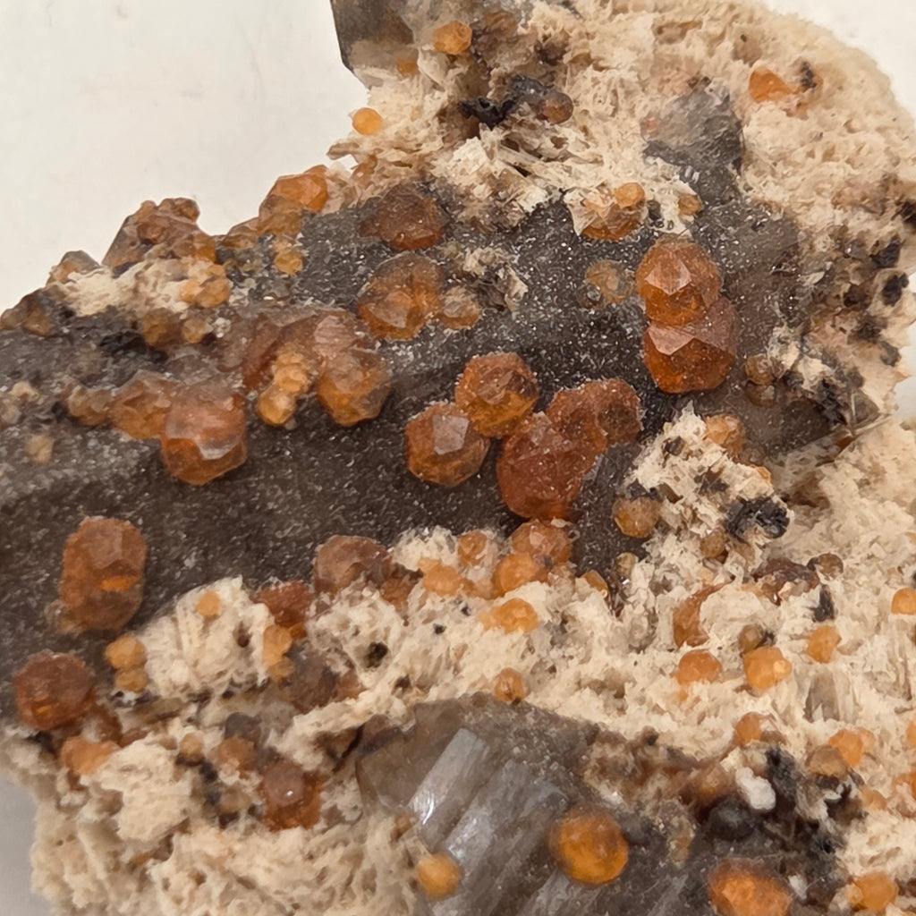Angled view of Fujian spessartine garnet and smoky quartz specimen