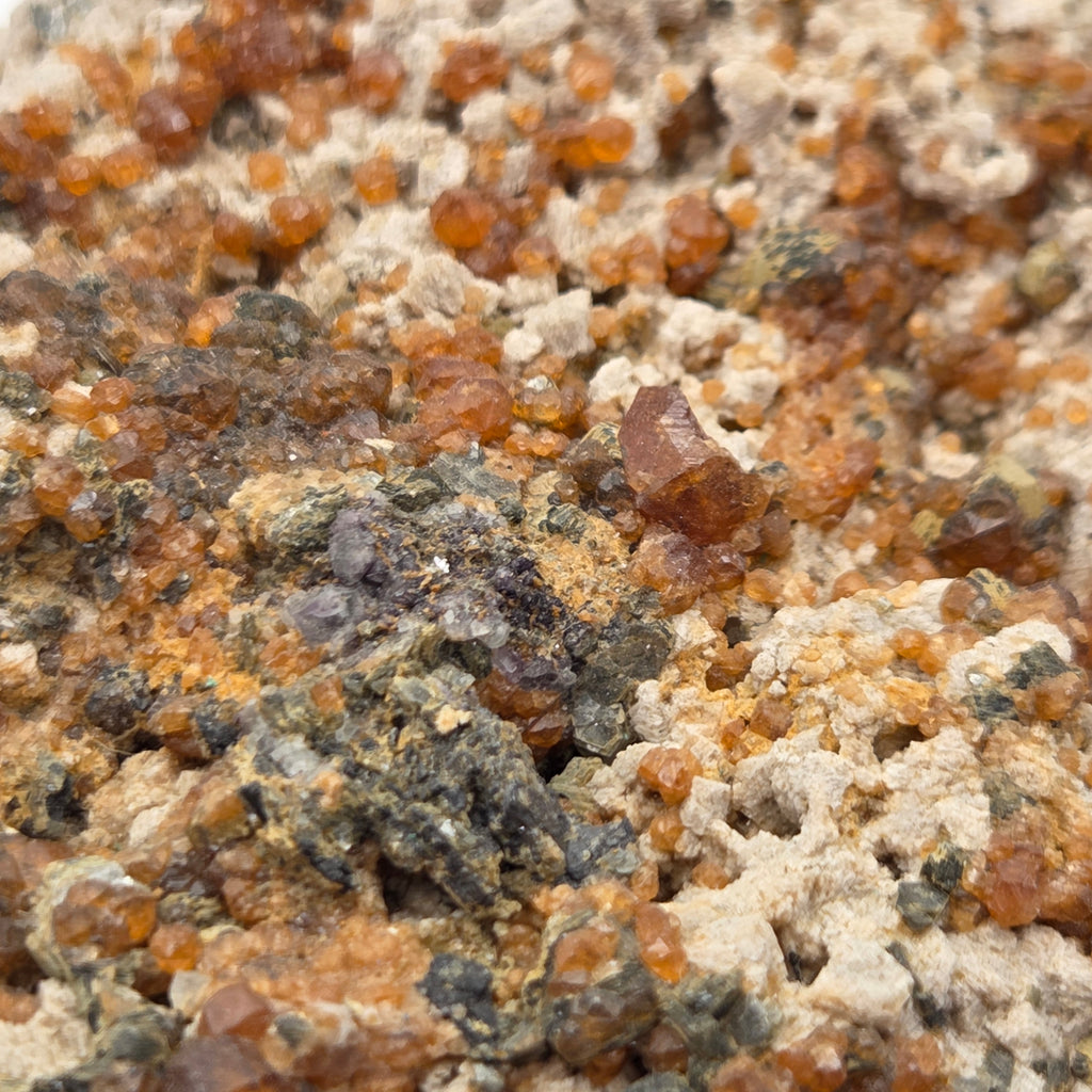 Close-up of spessartine garnet crystals with sparkling mica